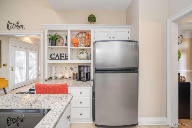 kitchen featuring white cabinets, freestanding refrigerator, light stone countertops, stovetop, and open shelves