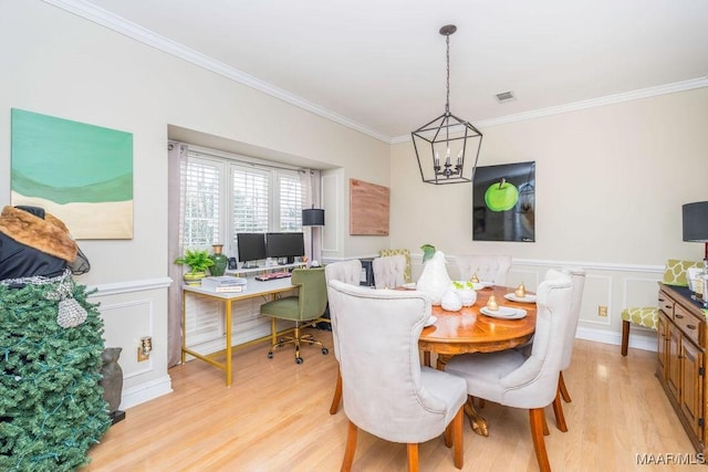 dining space featuring a wainscoted wall, visible vents, light wood-style flooring, an inviting chandelier, and ornamental molding