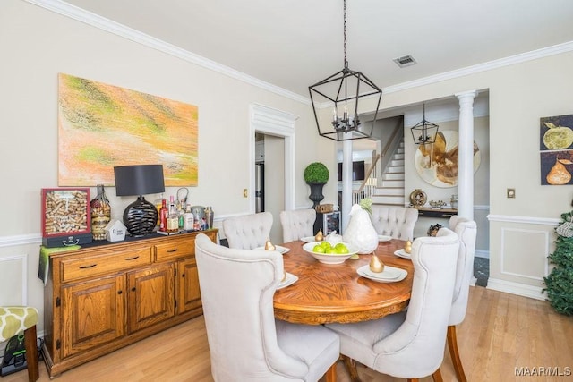 dining space with light wood-style floors, wainscoting, and crown molding