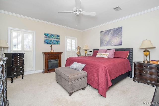 carpeted bedroom featuring visible vents, ornamental molding, and a glass covered fireplace