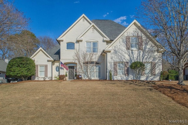 french provincial home featuring a front yard and brick siding