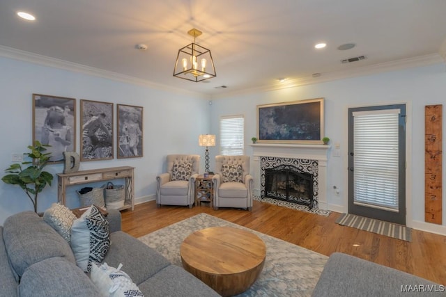 living area with visible vents, ornamental molding, wood finished floors, and a fireplace with flush hearth