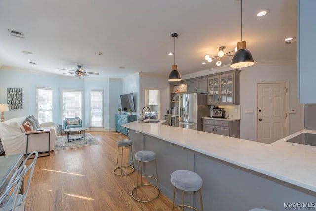 kitchen featuring light wood-type flooring, ornamental molding, stainless steel refrigerator with ice dispenser, and a sink