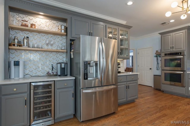 kitchen featuring gray cabinets, light countertops, appliances with stainless steel finishes, ornamental molding, and beverage cooler