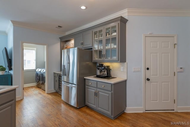 kitchen featuring light wood-type flooring, washer and dryer, gray cabinets, and stainless steel fridge with ice dispenser