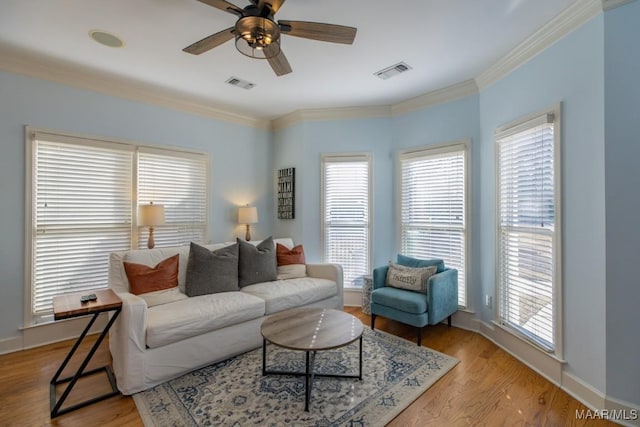 living room with light wood-type flooring, visible vents, and crown molding