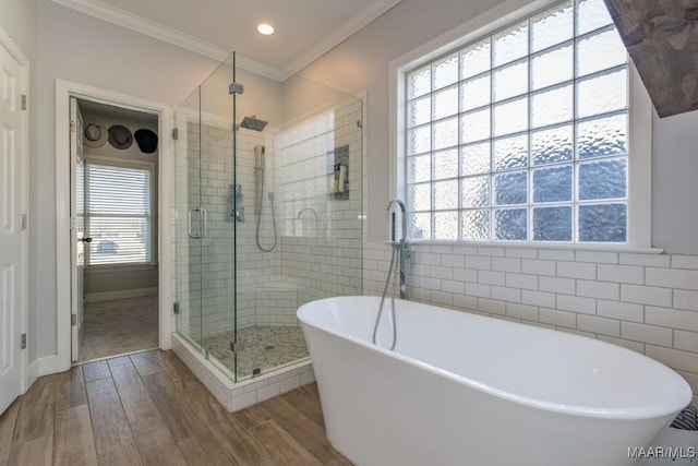 full bathroom featuring crown molding, tile walls, a freestanding bath, a stall shower, and wood finished floors