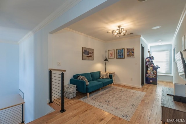 sitting room featuring light wood-style flooring, ornamental molding, baseboards, and an upstairs landing