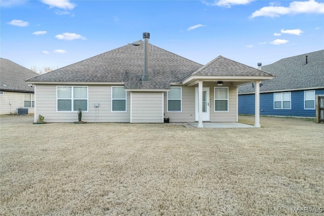 back of property featuring a shingled roof, central AC unit, a lawn, and a patio