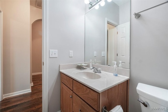 bathroom featuring baseboards, visible vents, toilet, wood finished floors, and vanity