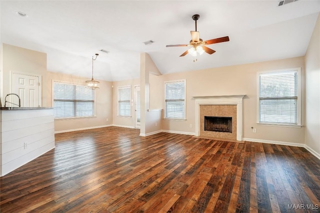 unfurnished living room with a healthy amount of sunlight, visible vents, vaulted ceiling, and dark wood-style flooring