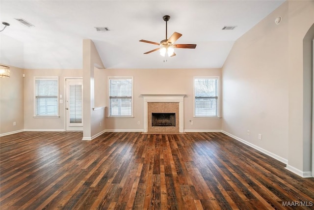 unfurnished living room with visible vents, vaulted ceiling, dark wood-type flooring, and a tile fireplace