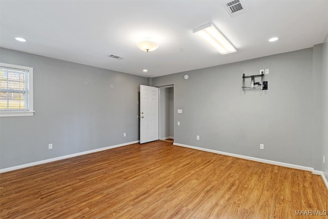 spare room featuring light wood-style floors, baseboards, and visible vents