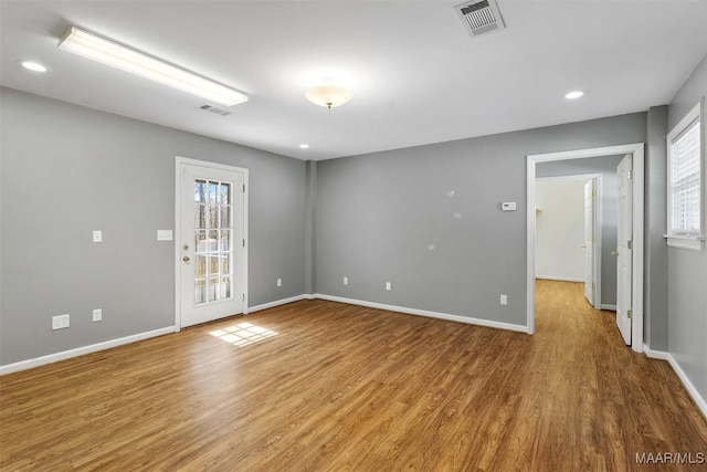 empty room featuring baseboards, visible vents, wood finished floors, and recessed lighting