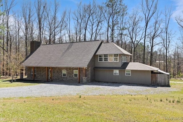 view of front of home featuring a front lawn, a chimney, and gravel driveway