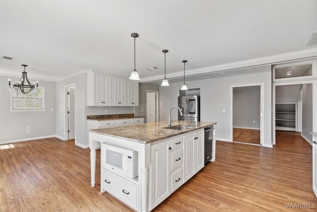 kitchen featuring white cabinets, an island with sink, stainless steel appliances, light wood-style floors, and a sink