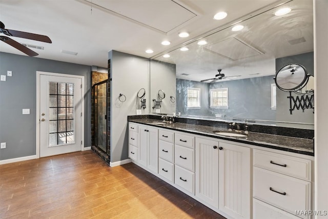 full bath featuring a stall shower, double vanity, a sink, and wood finished floors