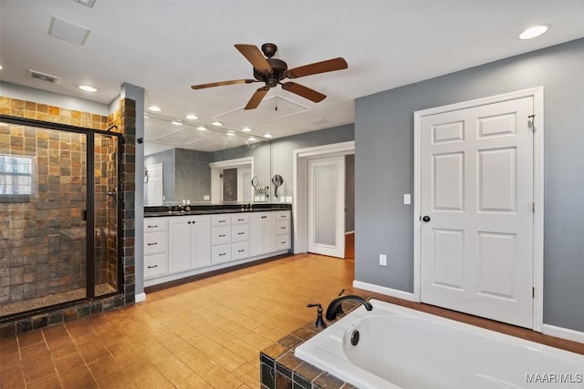 bathroom with a garden tub, double vanity, visible vents, a shower stall, and wood finished floors