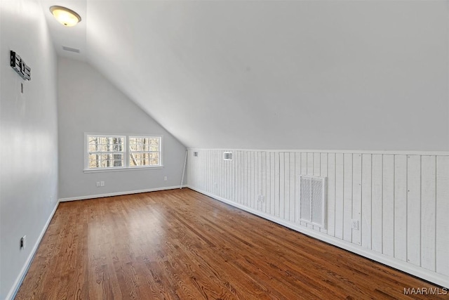 bonus room featuring baseboards, visible vents, vaulted ceiling, and wood finished floors