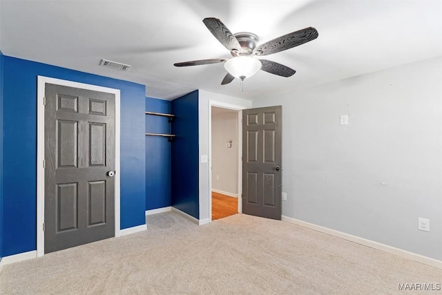 unfurnished bedroom featuring carpet floors, a closet, visible vents, a ceiling fan, and baseboards