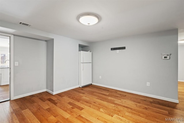 spare room with light wood-style floors, baseboards, visible vents, and a sink