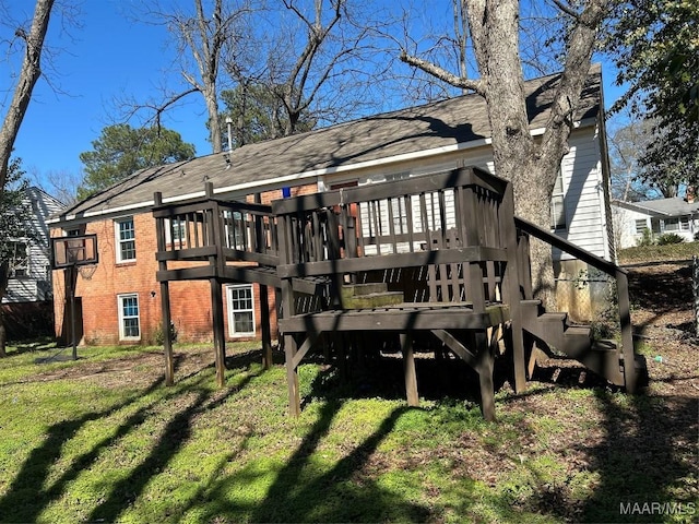 rear view of house with a yard, a deck, and brick siding