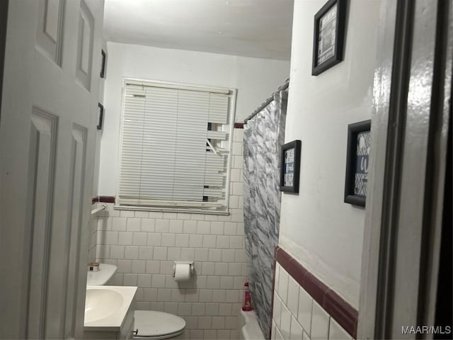 bathroom featuring a wainscoted wall, tile walls, toilet, and vanity