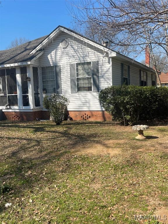 view of property exterior with a sunroom and a lawn