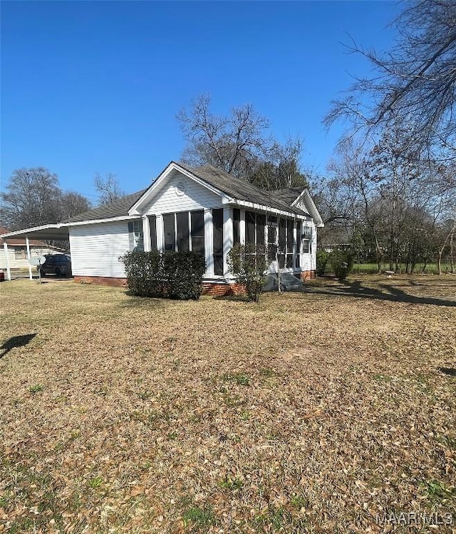 view of front of home featuring a front lawn, an attached carport, and a sunroom