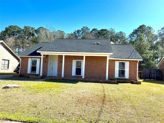 view of front of property with a shingled roof, a front yard, brick siding, and fence