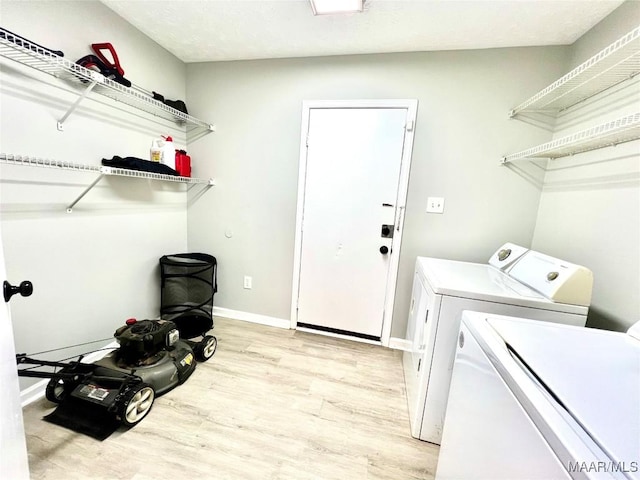 clothes washing area featuring light wood-style floors, laundry area, washer and clothes dryer, and baseboards