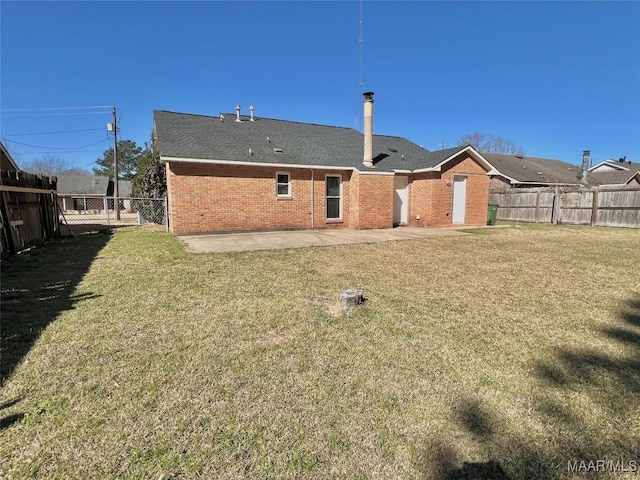 rear view of house with brick siding, a lawn, and a fenced backyard