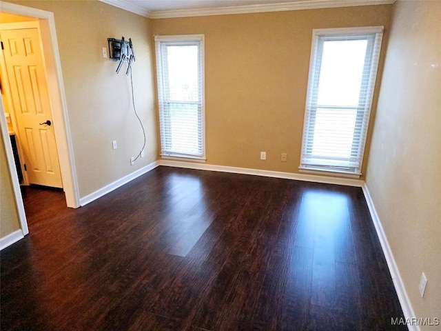 empty room with dark wood-style floors, baseboards, and crown molding