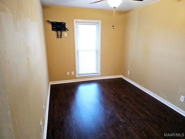 spare room featuring dark wood-style floors, ceiling fan, and baseboards