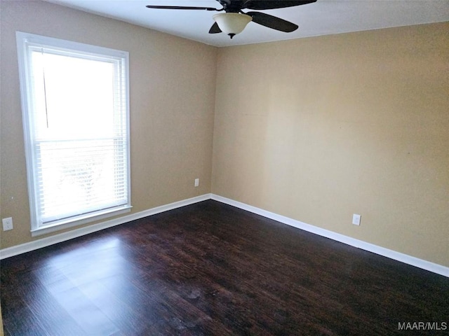 empty room featuring dark wood-style floors, baseboards, and a ceiling fan