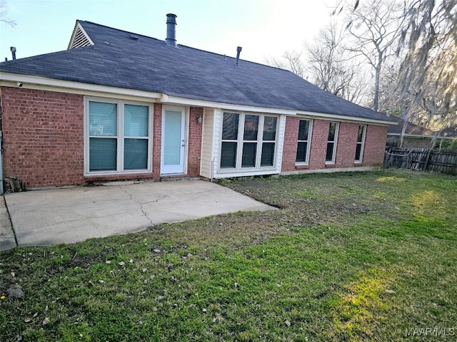 back of house with brick siding, fence, roof with shingles, a lawn, and a patio area