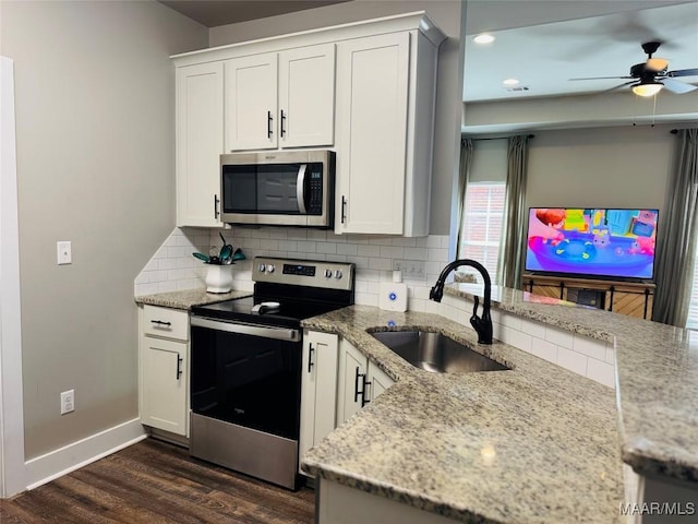 kitchen featuring light stone counters, appliances with stainless steel finishes, dark wood-type flooring, a sink, and backsplash