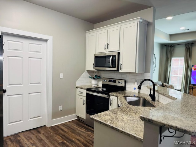 kitchen with tasteful backsplash, dark wood-style flooring, a peninsula, stainless steel appliances, and a sink