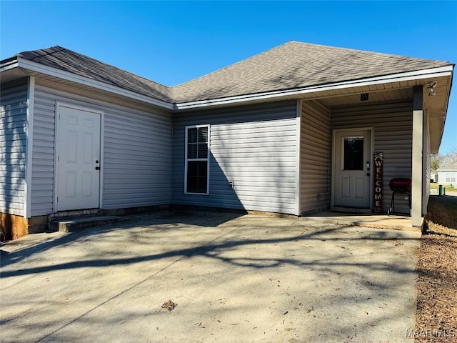 rear view of property with roof with shingles and a patio