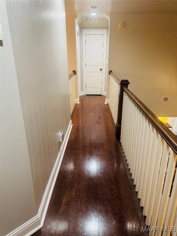 hallway featuring dark wood-style floors, visible vents, an upstairs landing, and baseboards