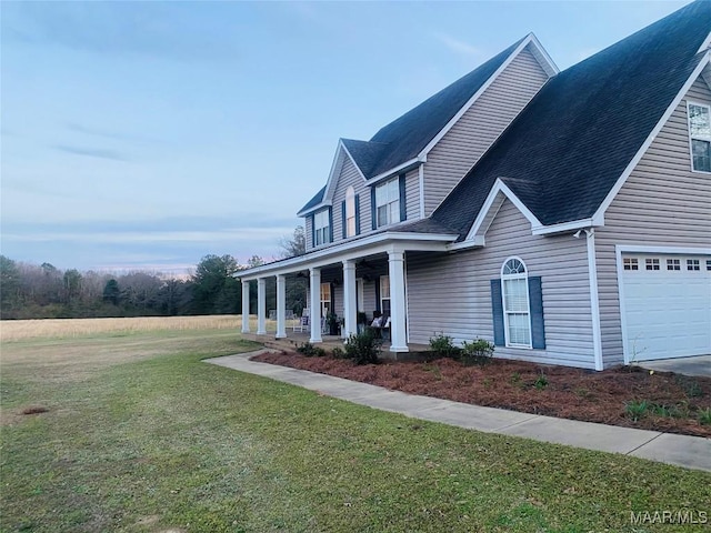 view of side of property with a garage, roof with shingles, a porch, and a lawn