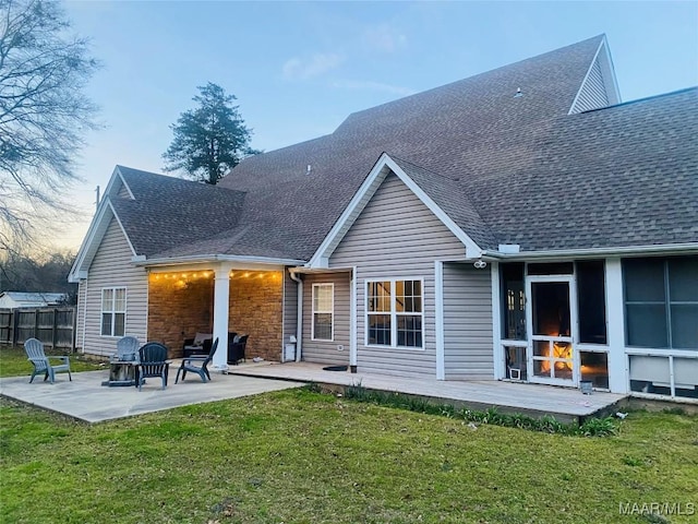 rear view of house featuring a shingled roof, a patio area, a yard, and fence