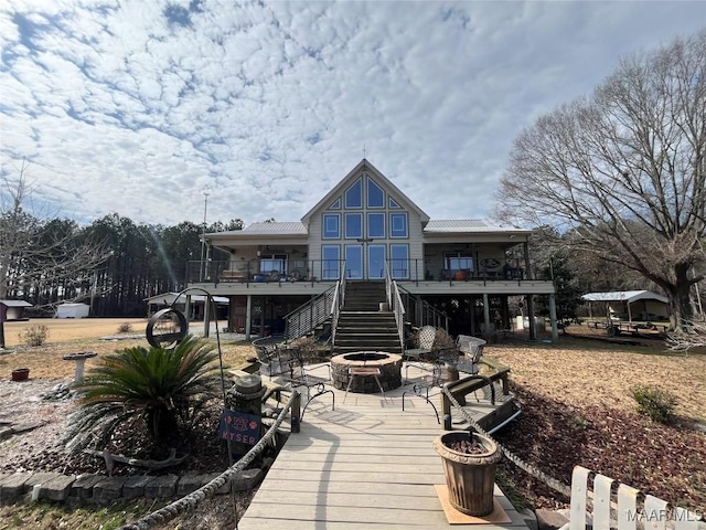 back of property featuring metal roof, a patio, an outdoor fire pit, stairway, and a wooden deck