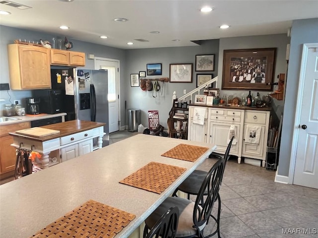 kitchen with light tile patterned floors, visible vents, light brown cabinetry, stainless steel refrigerator with ice dispenser, and recessed lighting