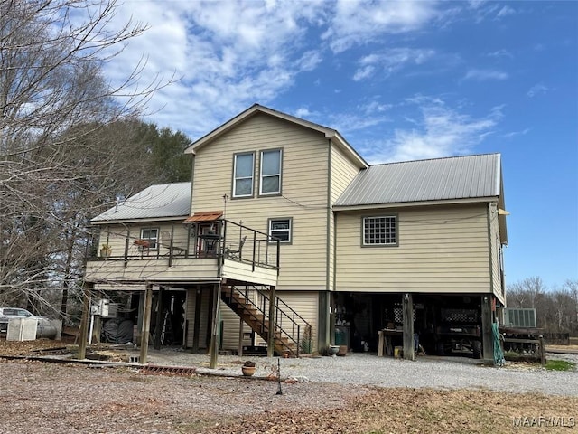 rear view of house with driveway, stairway, metal roof, a deck, and a carport