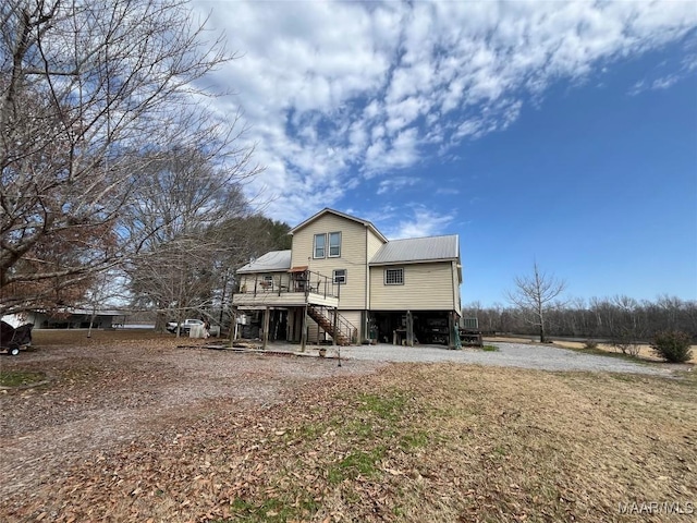 back of house with stairs, metal roof, a carport, and driveway