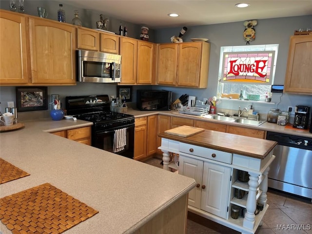 kitchen featuring dark tile patterned flooring, a kitchen island, appliances with stainless steel finishes, a sink, and recessed lighting