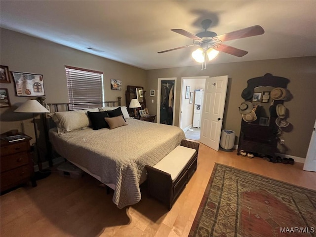 bedroom featuring light wood-style flooring, visible vents, a ceiling fan, a spacious closet, and a closet