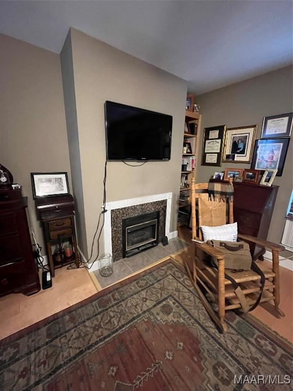 living area featuring wood finished floors, a glass covered fireplace, and baseboards