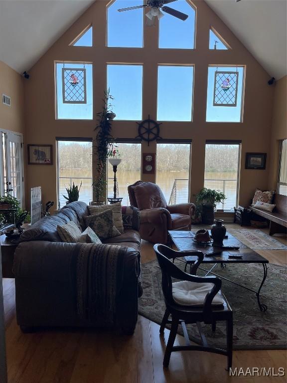 living area with high vaulted ceiling, ceiling fan, visible vents, and wood finished floors